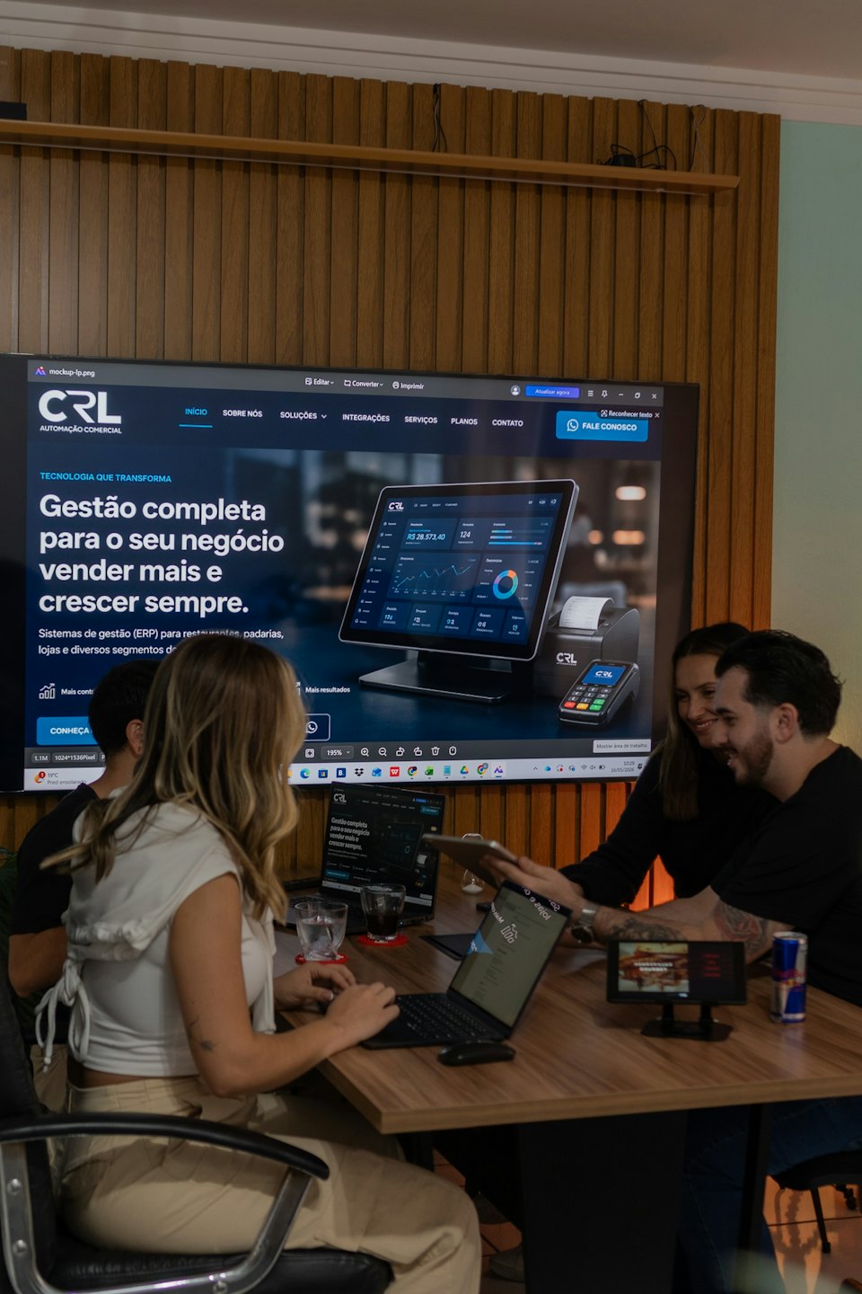 Équipe examinant le système ERP CRL Automação Comercial sur des ordinateurs portables et une tablette.