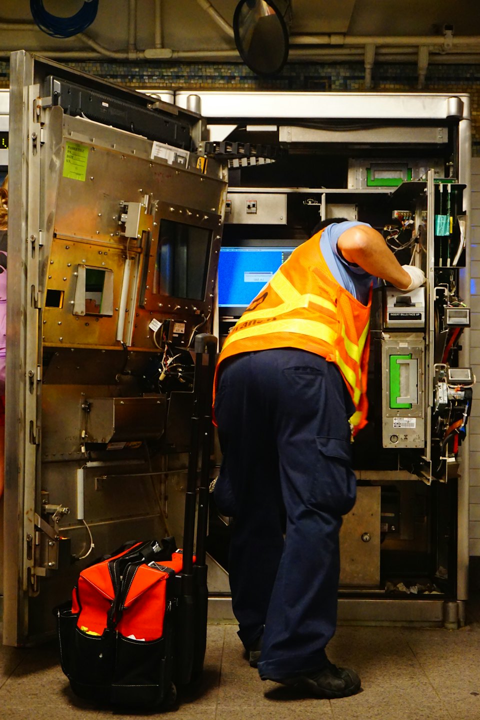 Technicien en chasuble de sécurité travaillant sur une machine de service public.